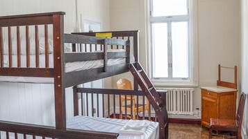 Dormitorio con literas, un radiador, una ventana y un escritorio.