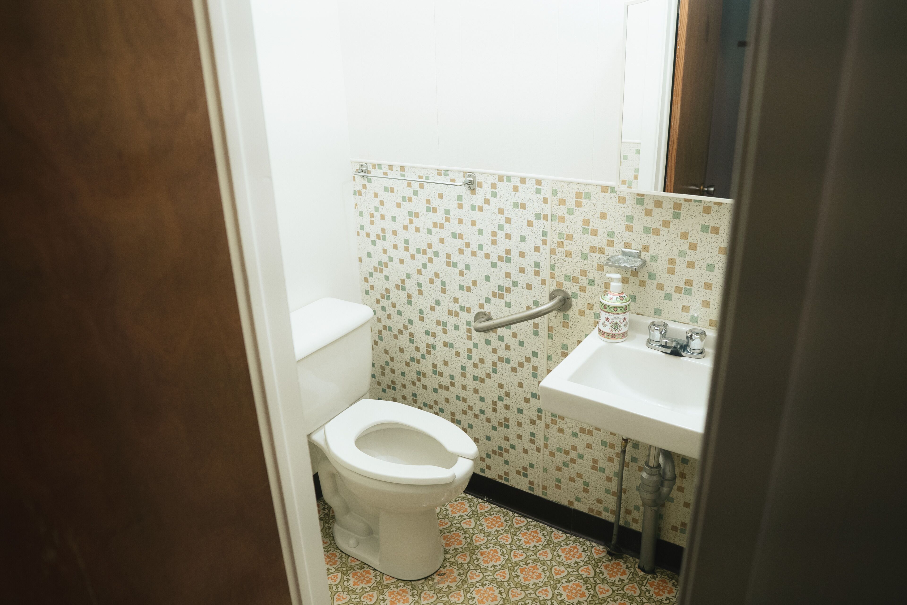A small bathroom with a toilet, sink, and a mirror.