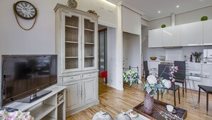 Un salon moderne doté d’un téléviseur à écran plat, d’un meuble blanc et d’un coin repas avec des chaises et une table.