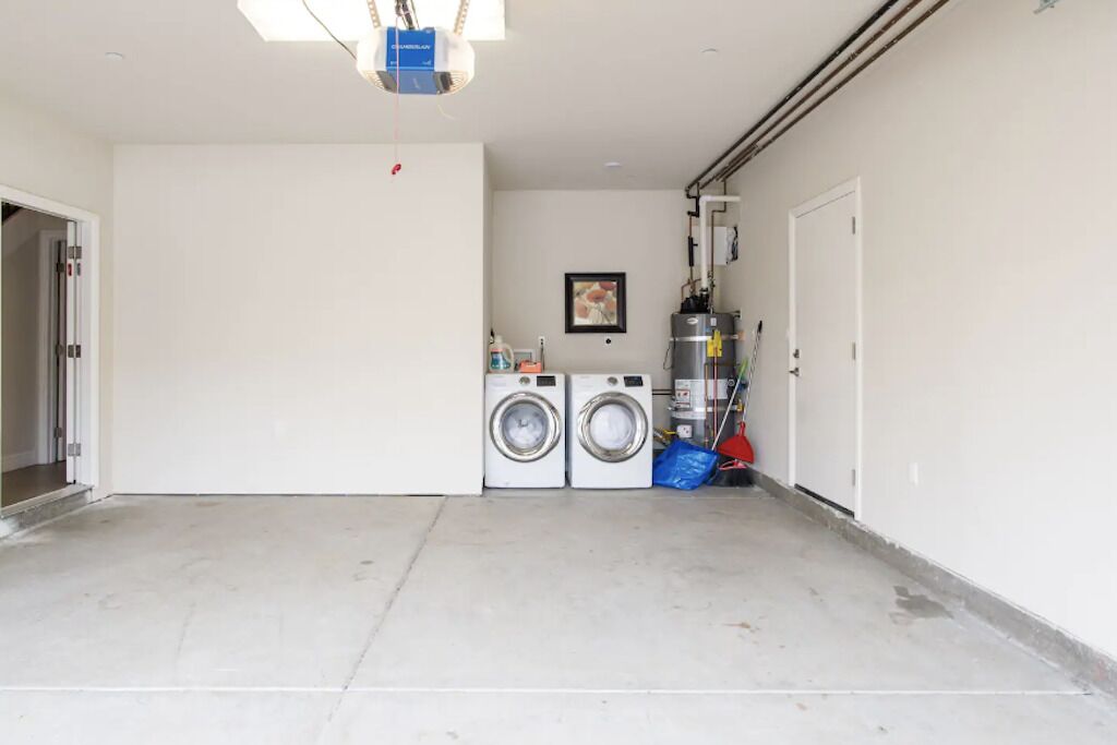 A laundry room with two washing machines, a ceiling light fixture, and a water heater.