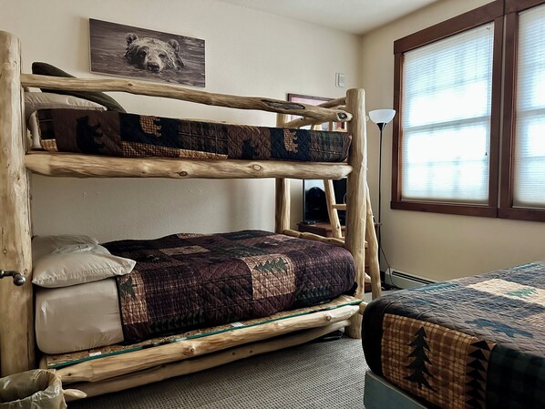 A bunk bed with a quilted blanket, a pillow, and a wooden headboard.