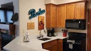 A kitchen with wooden cabinets, a microwave, a stove, a sink, and a bar area.