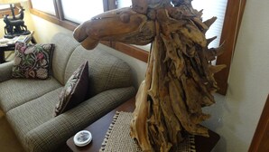 A rustic wooden sculpture on a table in a living room with a checkered sofa and decorative pillows.