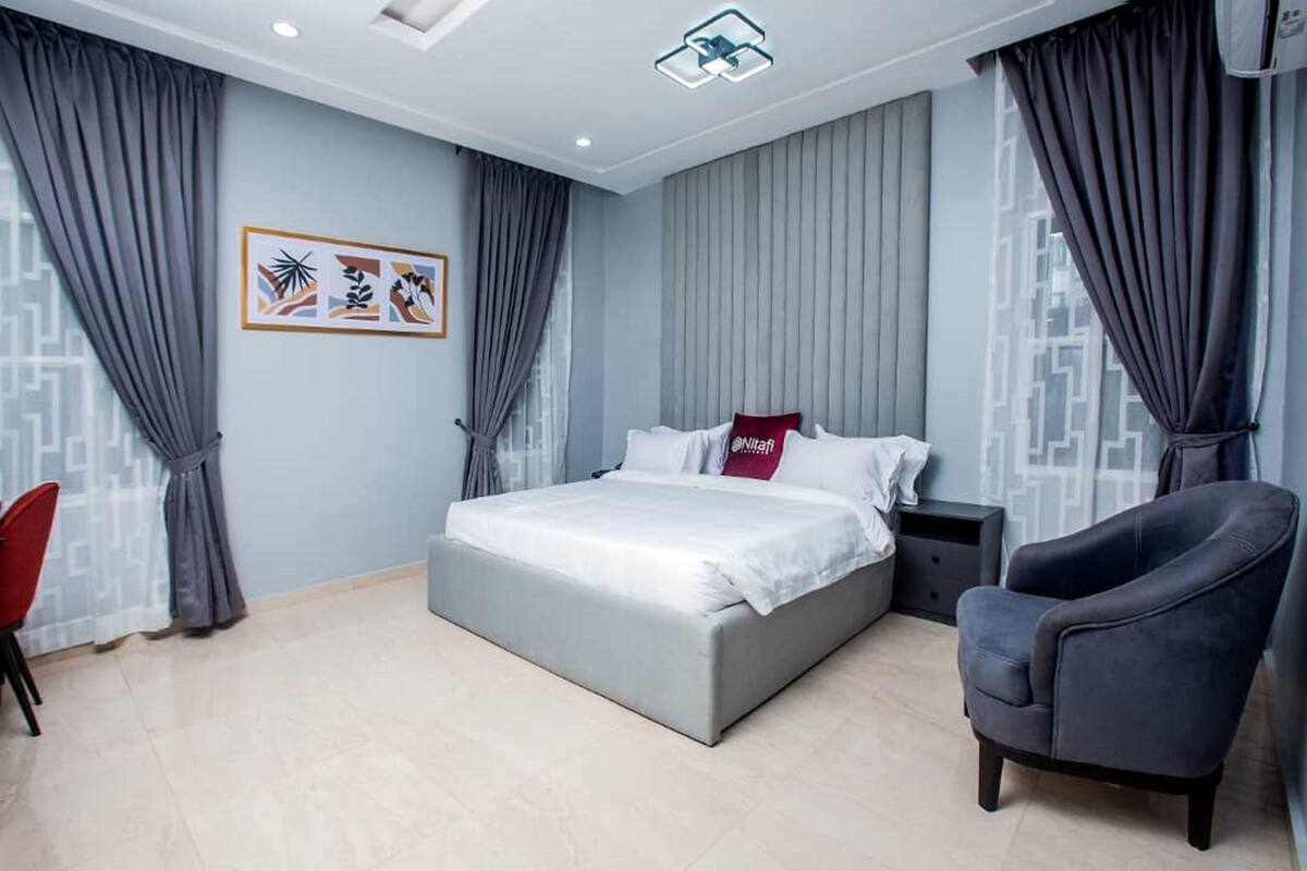 Un dormitorio moderno con cama, una silla y una mesita de noche.