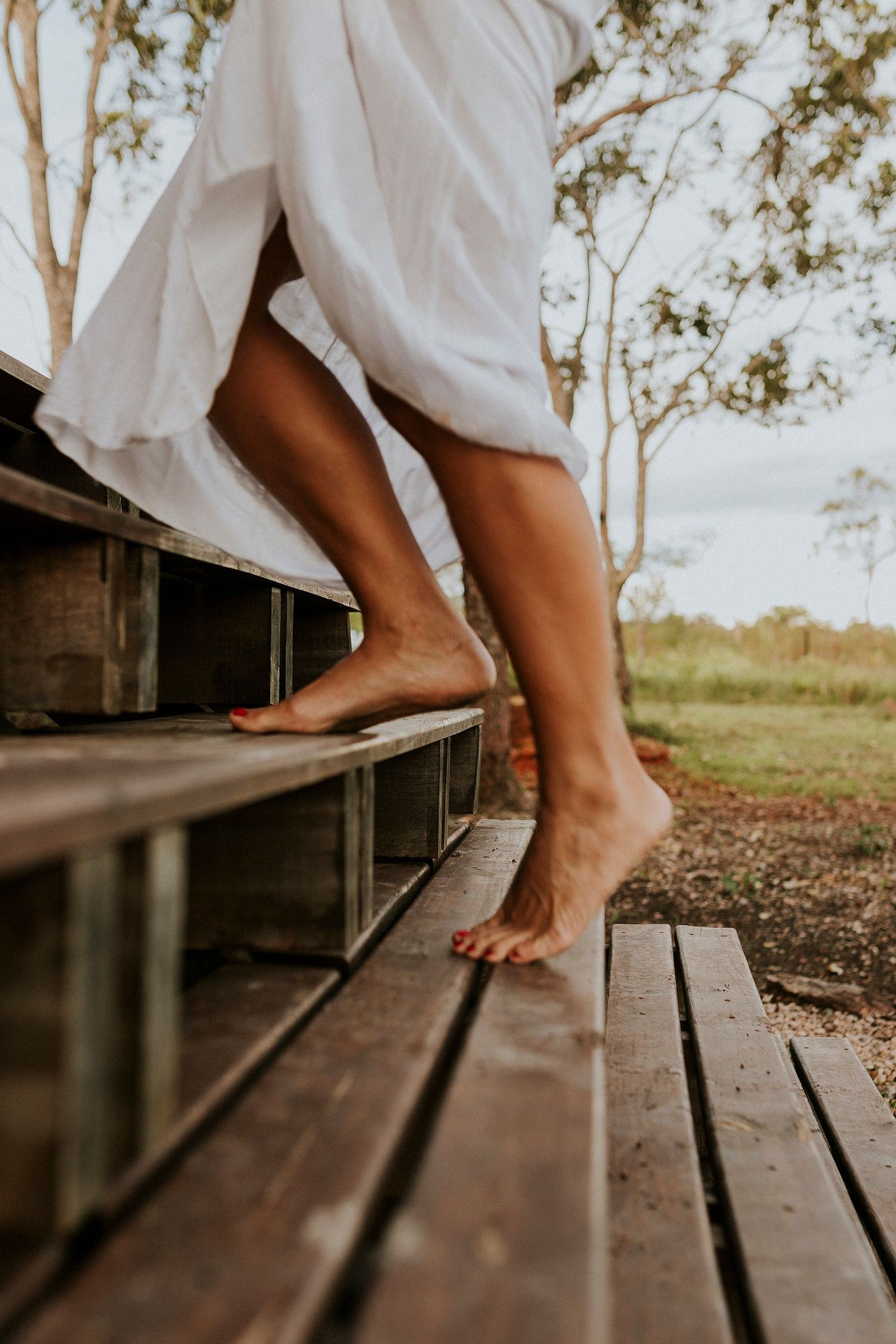 A wooden bench outdoors with a person sitting on it.
