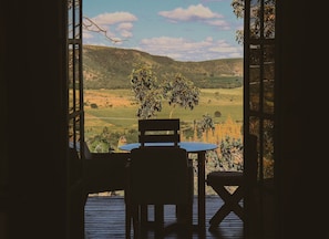 An open patio with a table and chairs, overlooking a hilly landscape with a clear sky. - MORRO DA LUZ (Alto Paraíso de Goiás)