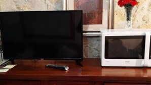 Un meuble de rangement en bois pour appareils électroniques, doté d’un téléviseur à écran plat et d’un four à micro-ondes blanc.