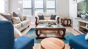 A living room with a sofa, two armchairs, a coffee table, and a television.