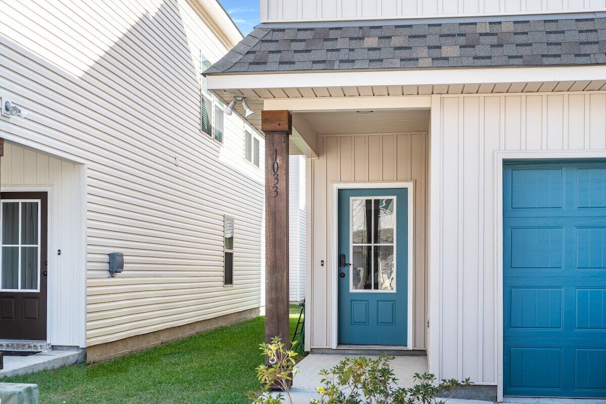 Una casa a due piani con una porta blu e un basculante garage.