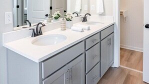 A bathroom with a double sink vanity, a large mirror, and a lighted vanity area. - Winners Paradise Steps from Tiger Country - BC1033 (Baton Rouge)
