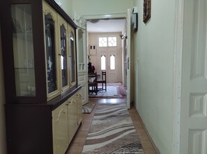 Un pasillo con un suelo estampado, una zona de comedor con sillas y una mesa, y un armario con puertas de cristal.