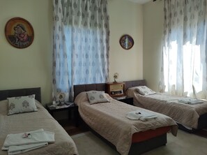 Una habitación de hotel con dos camas, una mesita de noche con una radio y un cuadro en la pared.