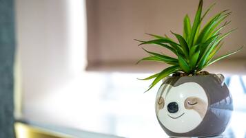 Un pot en céramique orné d’un motif représentant un visage de panda, dans lequel est plantée une plante verte.