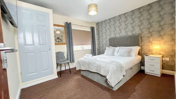 Une chambre à coucher comprenant un lit, une chaise, une table de chevet et une armoire.