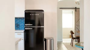 A modern kitchen with a black Galanz refrigerator, a blue tiled backsplash, and a wooden dining table with chairs. - NEW Modern 1940s Adobe - Downtown, Historic (Tucson)