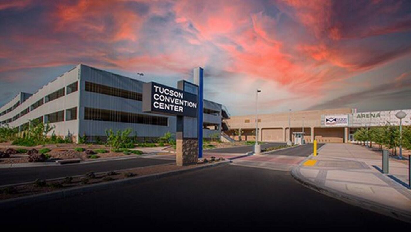 The Tucson Convention Center with a modern architectural design, featuring a prominent sign and a parking area.