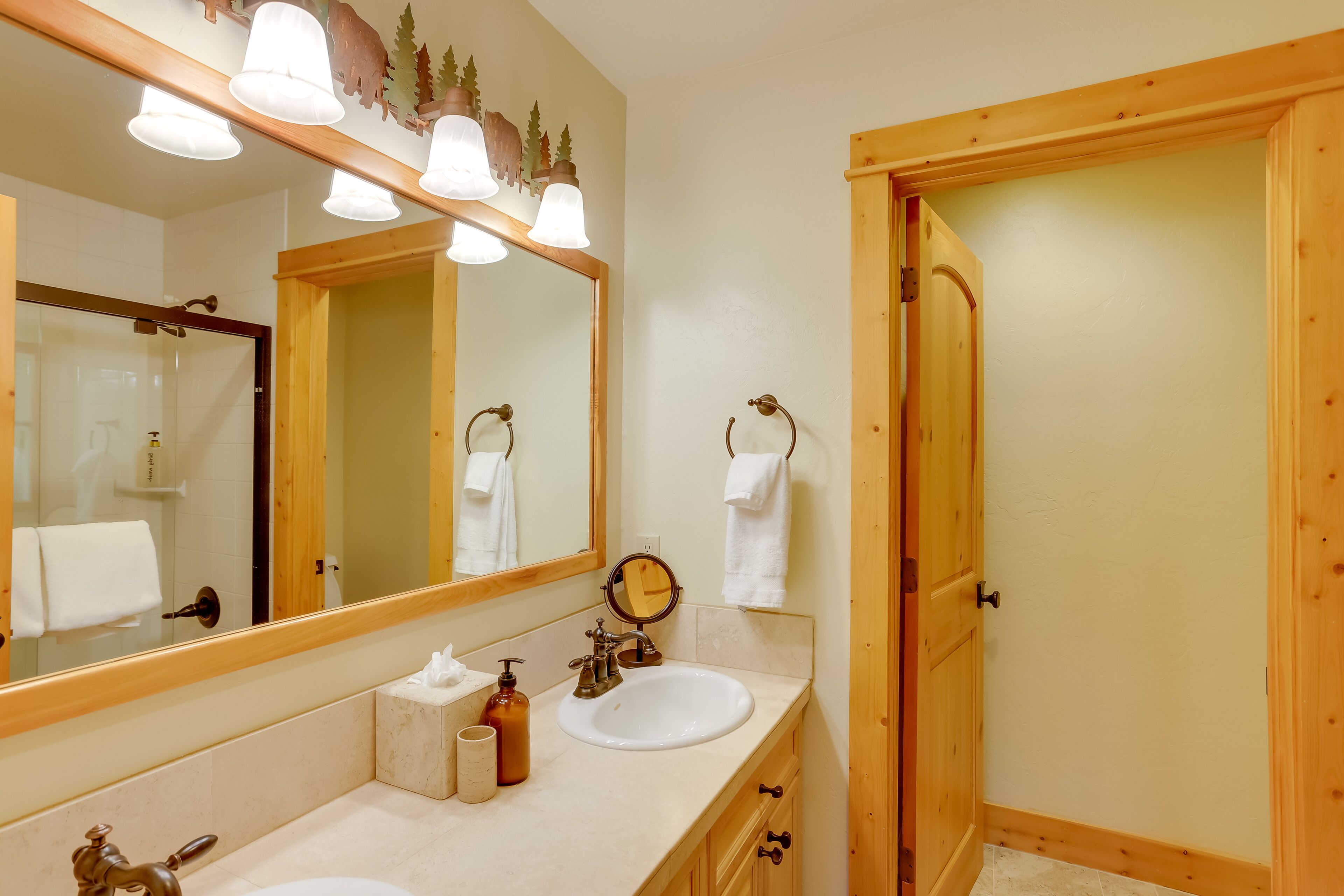 A bathroom with a wooden vanity, two sinks, a large mirror, and a towel rack.