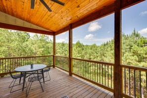Terraza de madera con una mesa y sillas, con vistas a un bosque.