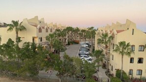 Een resort met meerlaags gebouwen, een parkeerplaats en palmbomen.