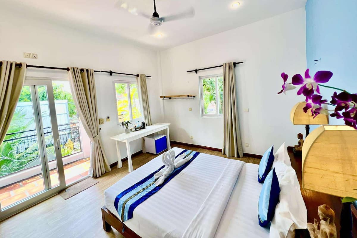 A hotel room with a bed, desk, and two windows.