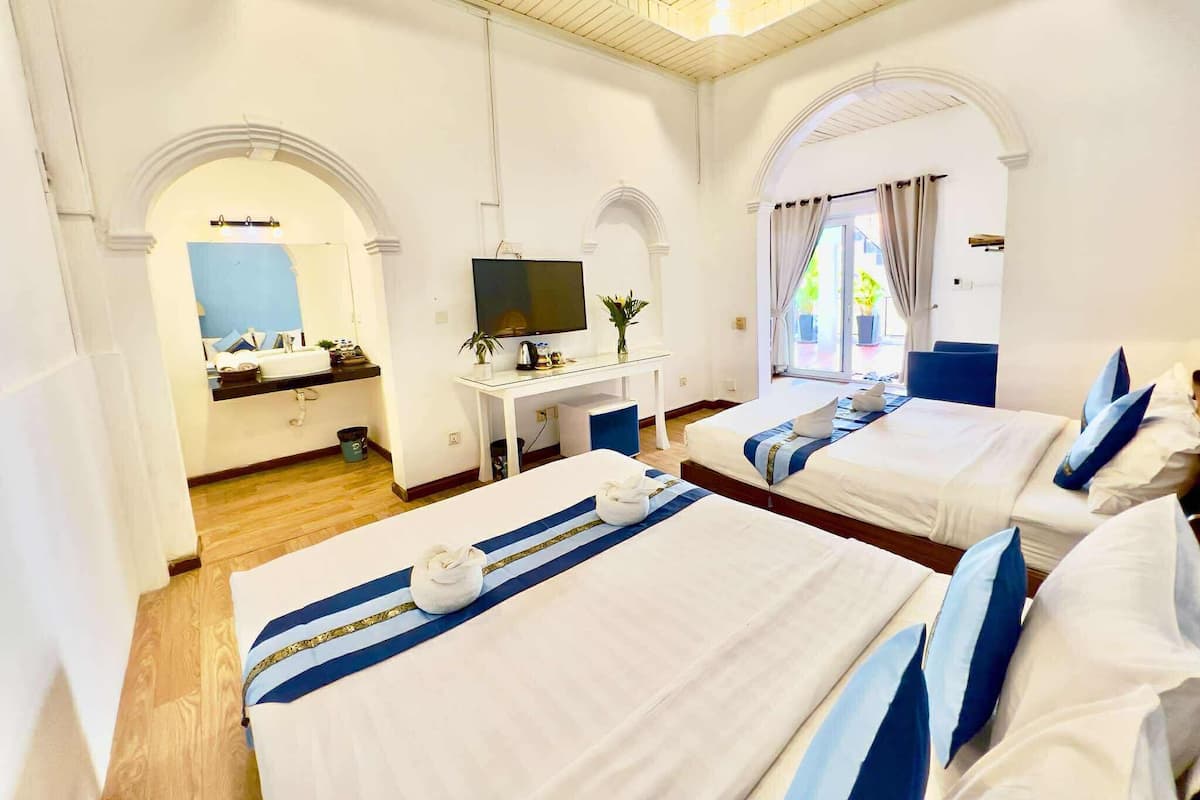 A hotel room with two beds, a TV, a desk, and a bathroom.