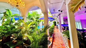 A spacious indoor area with a pool, surrounded by lush greenery and a bar area. - Pride Villa Cambodia (Phnom Penh)