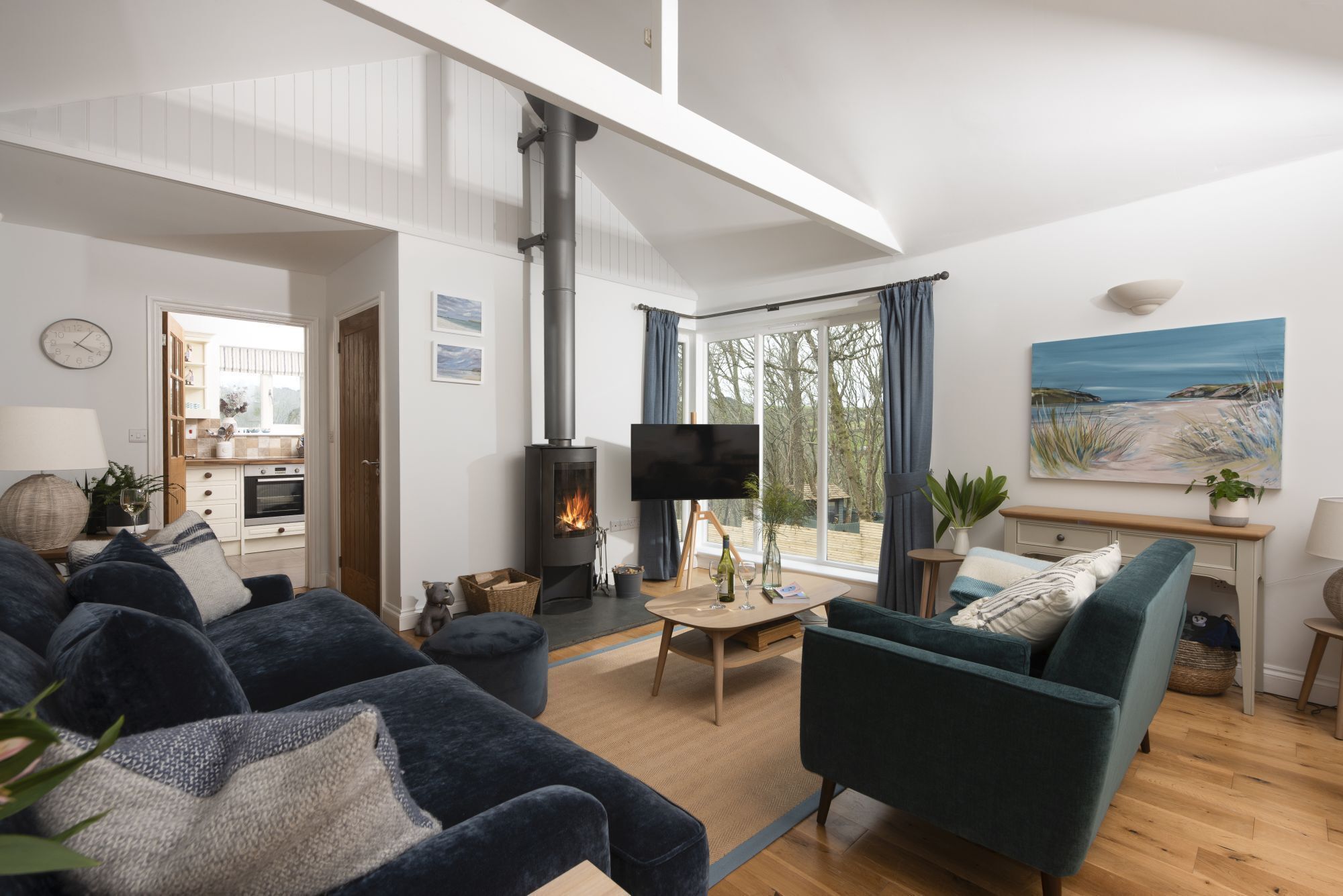 Ein modernes Wohnzimmer mit Kamin, bequemen Sitzmöglichkeiten und Blick ins Freie.