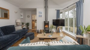 A cozy living room with a fireplace, a sofa, a coffee table, and a TV. - Lobbs Cottage -  Pet Friendly, Free Parking (St Mawgan)