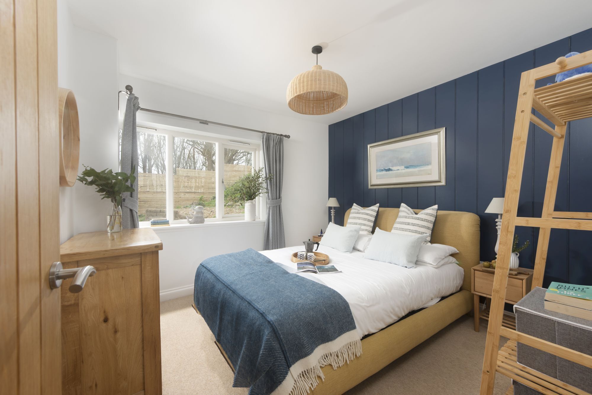 A bedroom with a bed, bedside tables, a window, and a hanging light fixture.