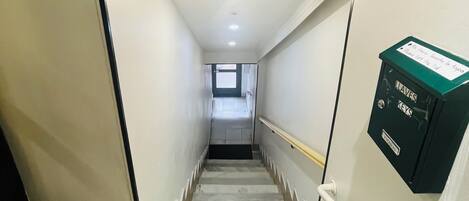 A hallway with a sign reading "SALIDA" at the top, a staircase with a handrail, and a box labeled "LLAVES KEYS" on the right wall.