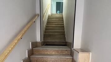 Una escalera con escalones de mármol y barandillas de madera, que conduce a una puerta en la parte superior.