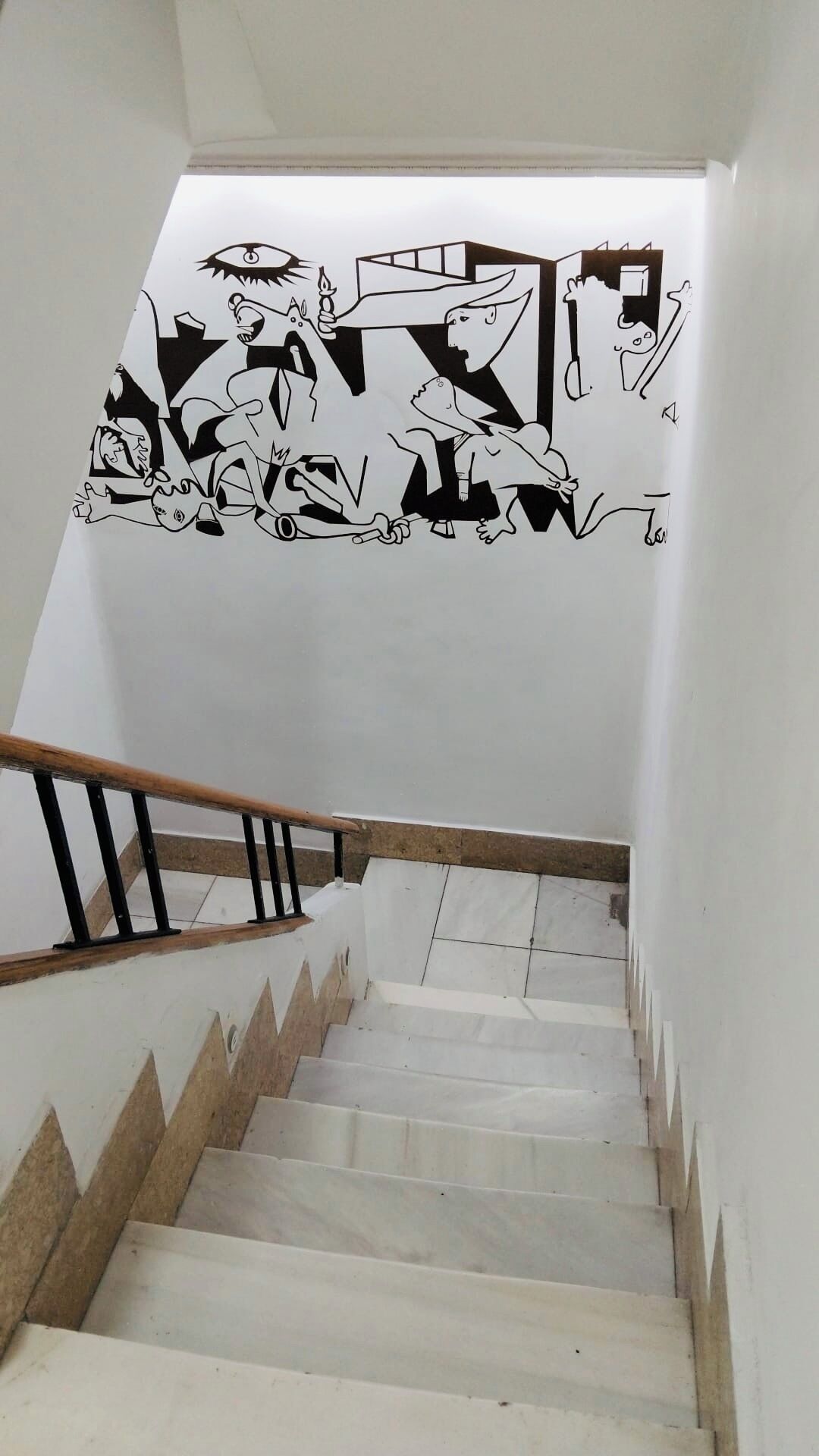 A staircase with a black and white mural on the wall.