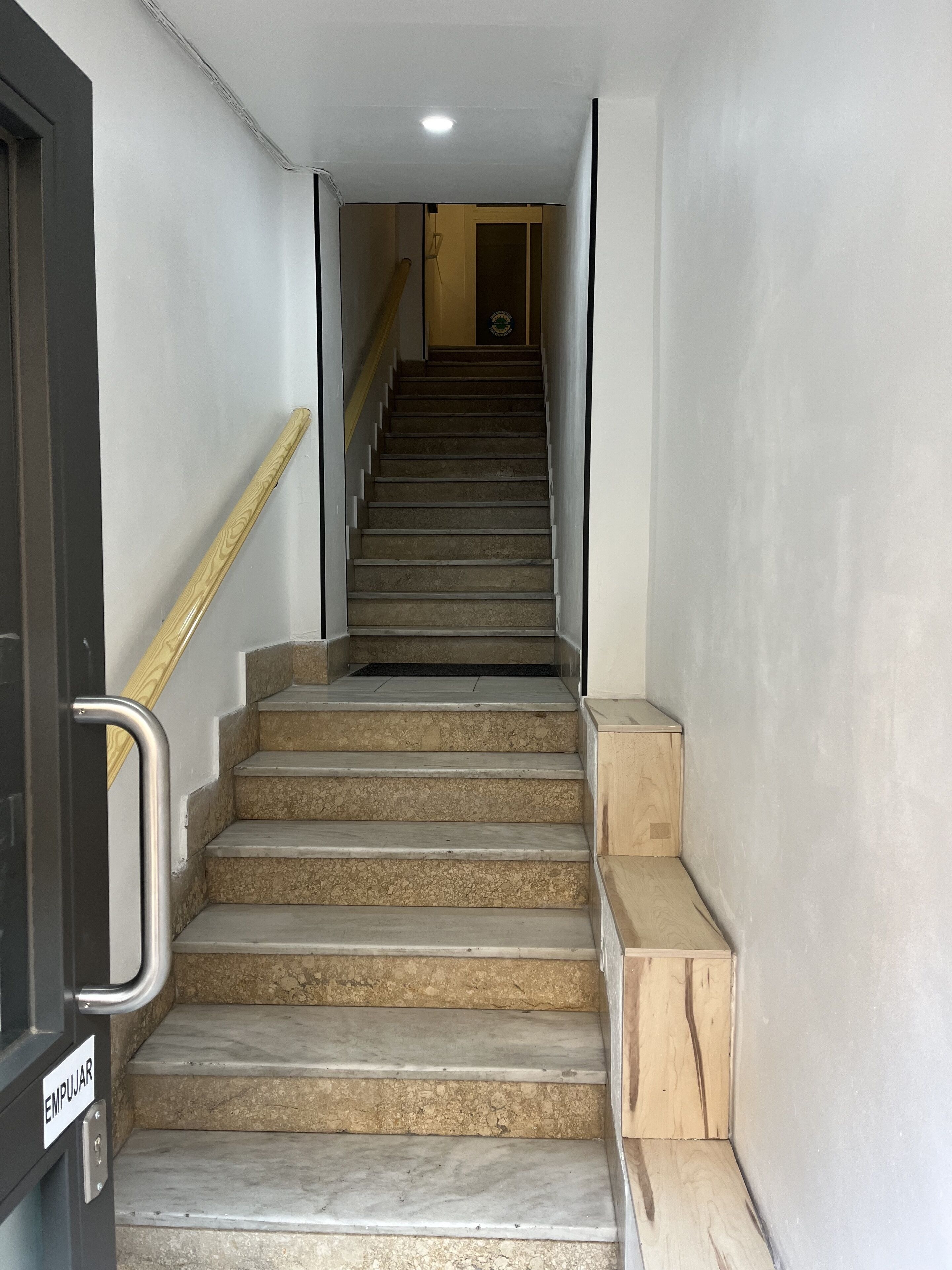 A staircase with a handrail, leading to a door labeled "EMPUJAR".