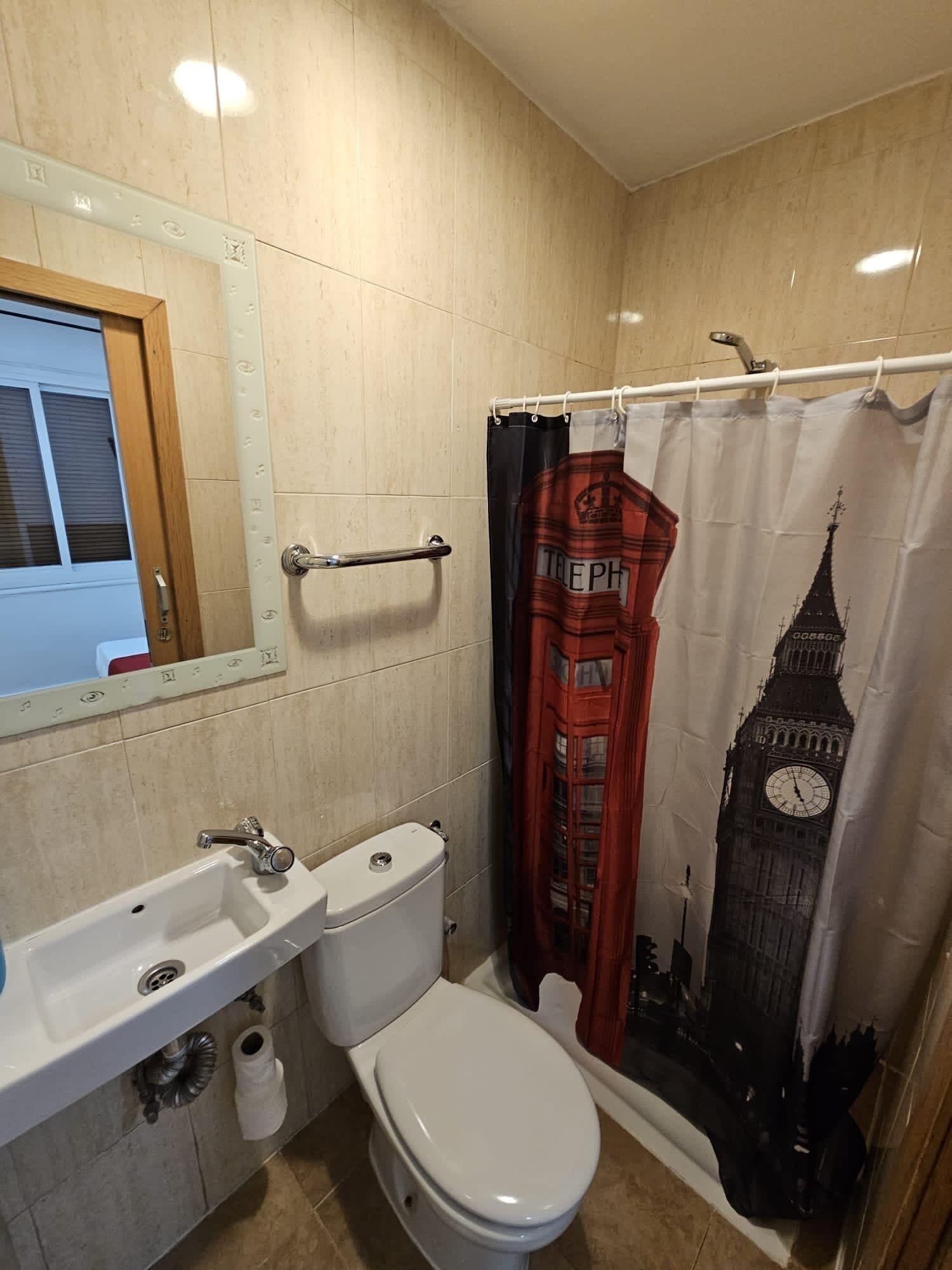 Ein Badezimmer mit Toilette, Waschbecken und Duschvorhang, das einen berühmten Glockenturm zeigt.