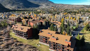 A multi-story hotel with a central courtyard, surrounded by autumn-colored trees and a mountain in the background. - Frisco Gateway to Skiing: Min to Breck + Keystone, Hot Tubs, Pickleball, Sauna (Frisco)