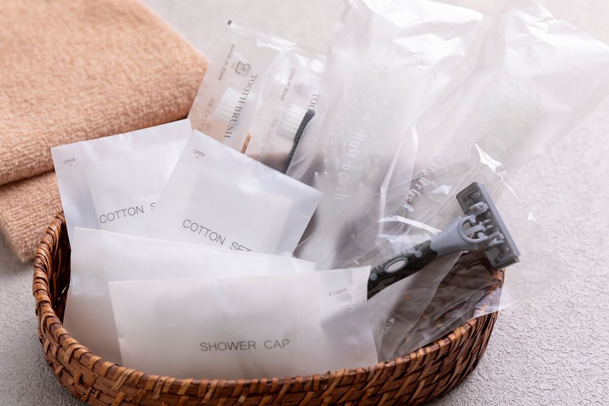 A wicker basket containing a shower cap, cotton sets, and a toothbrush.