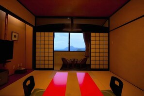 A traditional Japanese room with tatami flooring, a low table with chairs, and a view of a mountain through a shoji screen. - Nagomi no Yado Mutsuki (Beppu)