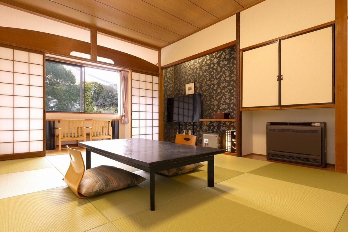 Una habitación japonesa tradicional con suelo de tatami, una mesa baja, puertas correderas y una chimenea.
