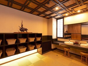 A bathroom with a wooden ceiling, a large mirror, a sink, and wicker baskets on shelves. - Nagomi no Yado Mutsuki (Beppu)