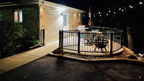 Ein Ziegelhaus mit überdachter Terrasse, einem Grill und Sitzgelegenheiten im Freien.