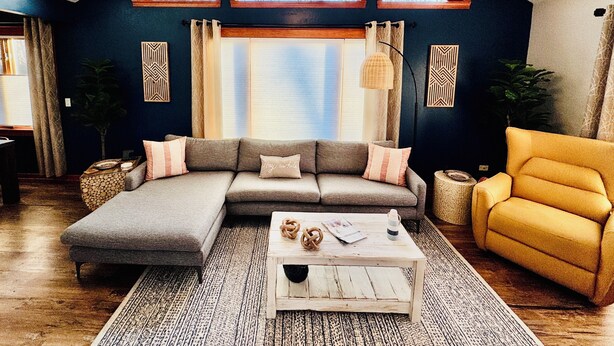 Ein gemütliches Wohnzimmer mit einem Ecksofa, einem gelben Sessel und einem Couchtisch.