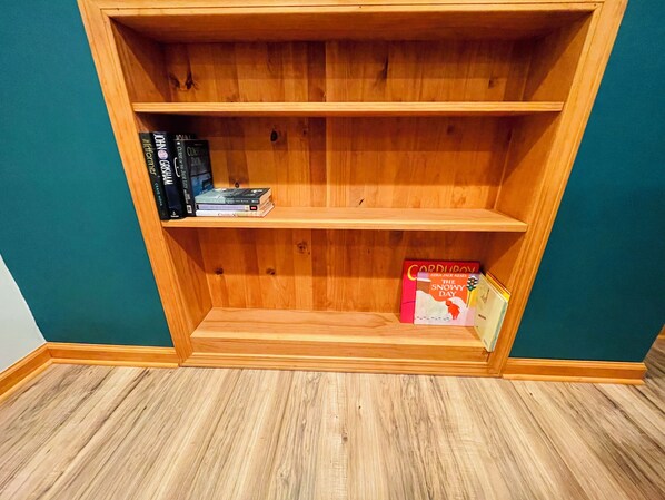 A wooden bookshelf with three shelves, some books, and a box. - Cozy Getaway by the Lake
(Twin Lakes)