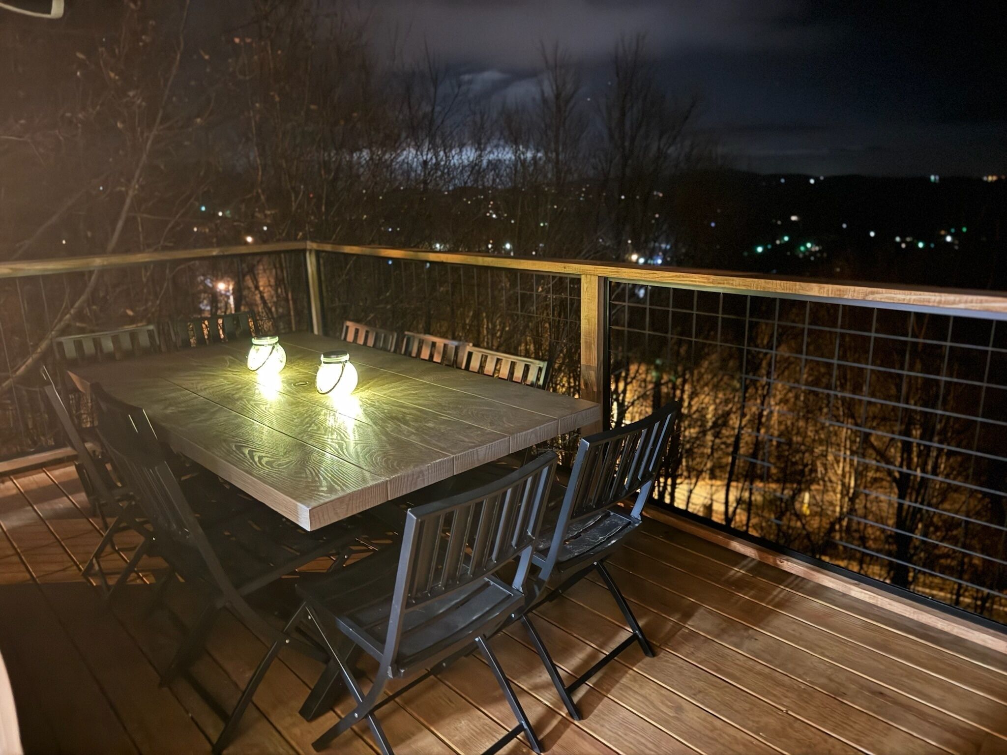 An outdoor deck with a rectangular table and chairs, surrounded by a wooden railing.