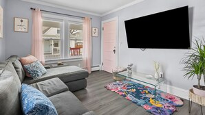 Un salon moderne avec un canapé gris, une table basse en verre et un tapis coloré.