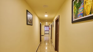 Un pasillo de hotel con piso de mármol, cuadros en las paredes y una puerta a la derecha.