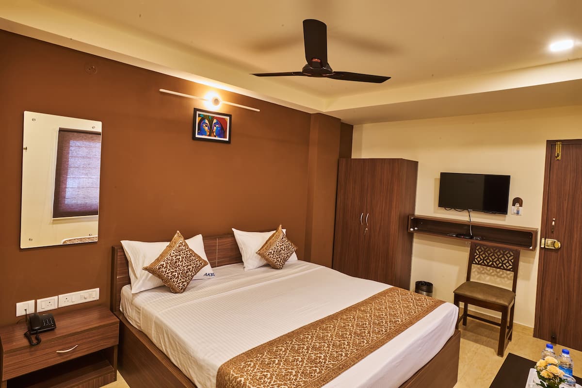 A hotel room with a bed, a desk, a television, and a ceiling fan.