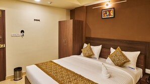 Una habitación de hotel con una cama grande, un armario, un cubo de basura y un cuadro en la pared.