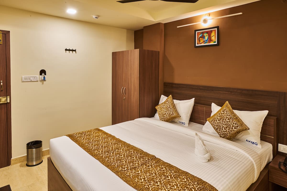 A hotel room with a large bed, a wardrobe, a trash bin, and a painting on the wall.