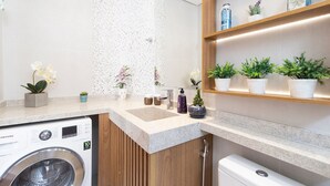 Ein modernes Badezimmer mit Waschmaschine, Waschbecken und Regalen mit Pflanzen.