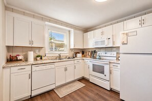 A kitchen with white cabinets, a microwave, an oven, and a dishwasher.